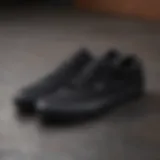 A close-up of all black low top Vans on a skateboard